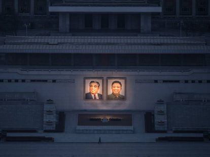 Homem passeia sob os dois grandes retratos de Kim Il-sung (esq.) e Kim Jong-il (dir.) em Pyongyang.