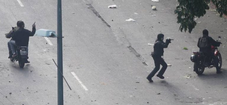 Paramilitares apontam armas para os manifestantes.