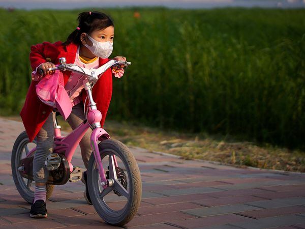 A girl wearing a face mask rides her bicycle  at a park after the lockdown was lifted in Wuhan, capital of Hubei province and China's epicentre of the novel coronavirus disease (COVID-19) outbreak, April 12, 2020. REUTERS/Aly Song