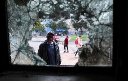 Um homem olha através da janela quebrada de uma delegacia de polícia destroçada logo depois de um protesto em Bogotá, em 5 de maio.