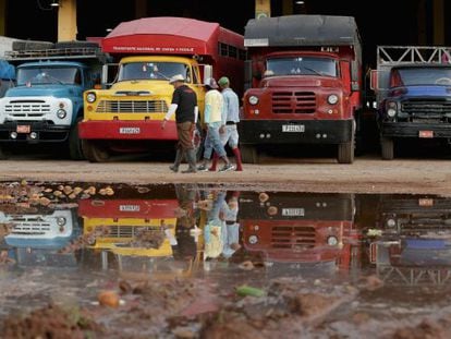 Um grupo de trabalhadores passa diante de caminhões em Havana.