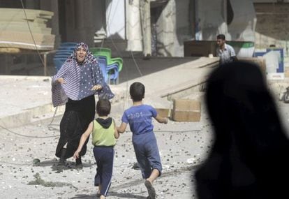 Mulher corre para pegar seus filhos após um bombardeio em Idlib, na Síria.
