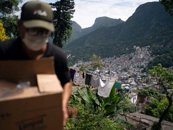 A local volunteer carries a package with soap and detergent to be distributed in an effort to stop the spread of the new coronavirus in the Rocinha slum of Rio de Janeiro, Brazil, Tuesday, March 24, 2020. (AP Photo/Leo Correa)
