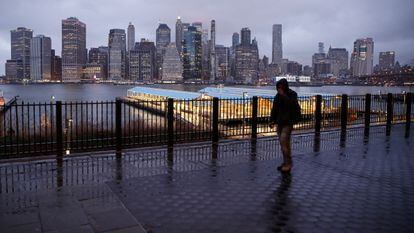 Homem caminha por uma rua deserta diante dos prédios de Manhattan.