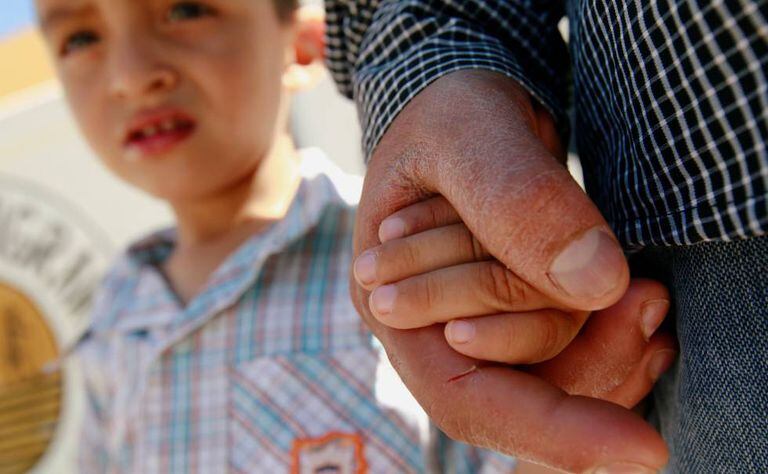 Imigrante salvadorenho Epigmenio Centeno segura a mão de seu filho, Steven.