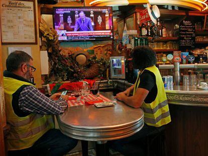 Dois coletes amarelos ouvem Philippe na televisão na quarta-feira, em um bar em Paris.
