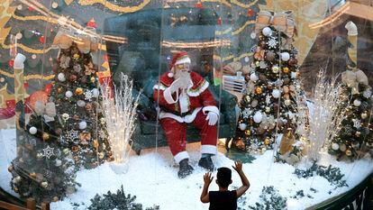 Abilio Nunes, artista do Papai Noel, acena para crianças de dentro de uma bolha, em um shopping de Brasília.