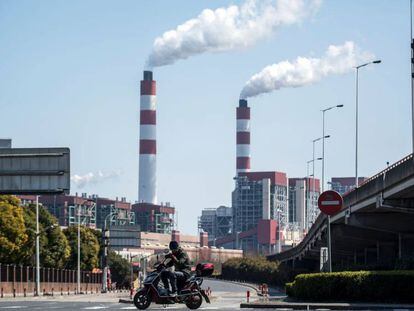 Um motociclista passa em frente a chaminés de uma central de geração elétrica em Xangai (China).