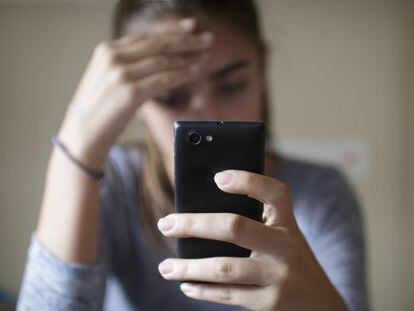 Uma adolescente cabisbaixa depois de receber uma ameaça por meio de seu celular.