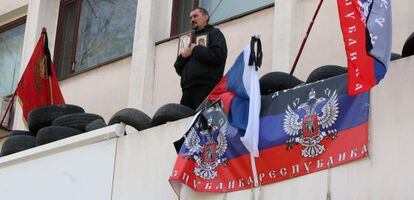 Um ativista pró-Rússia reza na varanda do edifício do governo de Mariupol.