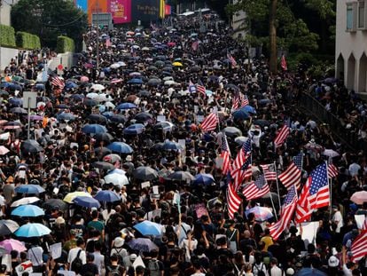 Os manifestantes levam guarda-chuvas e a bandeira dos EUA, no domingo, em Hong Kong.