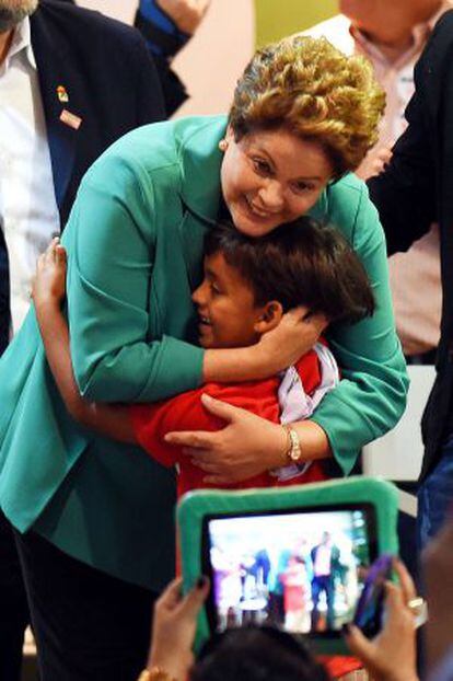 Dilma Rousseff abra&ccedil;a garoto em evento com trabalhadores rurais.