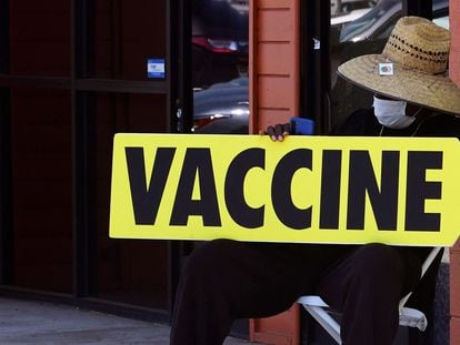 Um homem segura um cartaz indicando um centro de vacinação, em Los Angeles (Califórnia).