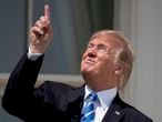 FILE - In this Aug. 21, 2017, file photo, President Donald Trump points to the sun as he arrives to view the solar eclipse at the White House in Washington. Trump's comment about injecting disinfectant to fight coronavirus is just the latest in a long list of comments and actions that run contrary to mainstream science. He's gone against scientific and medical advice by staring at an eclipse without protection, calling climate change a hoax and saying wind turbines cause cancer.  (AP Photo/Andrew Harnik, File)