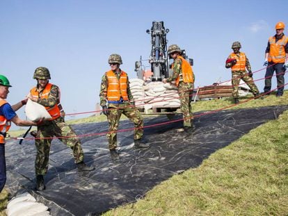 Vários soldados colaboram para reforçar um dique na Holanda.