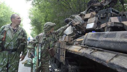 Militantes pró-russos observam os restos carbonizados de um tanque ucraniano perto de Donetsk.