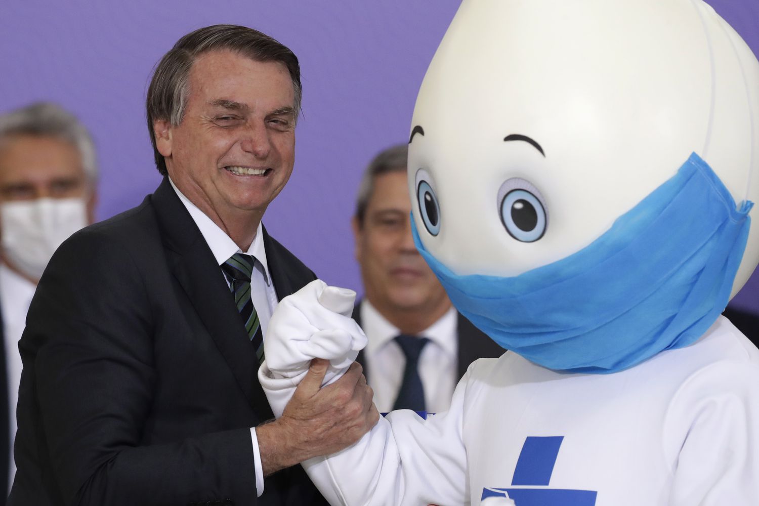Bolsonaro segura o braço de Zé Gotinha em dezembro após mascote se negar a cumprimentá-lo com aperto de mão.