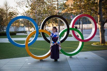 Japonesa vestida com um quimono diante dos anéis olímpicos de Tóquio