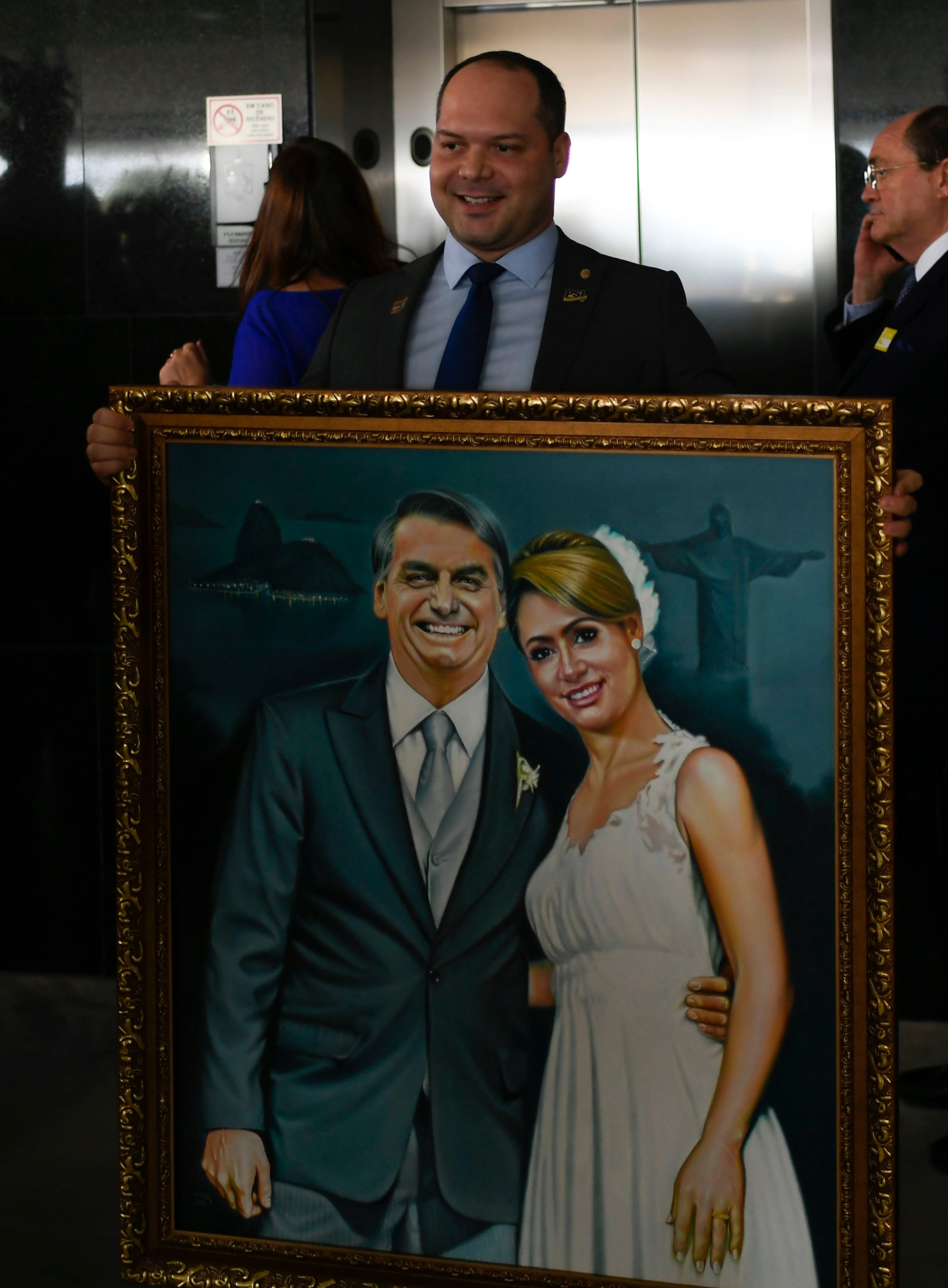 Heitor Freire segura uma pintura de Bolsonaro e sua esposa em fevereiro de 2019.