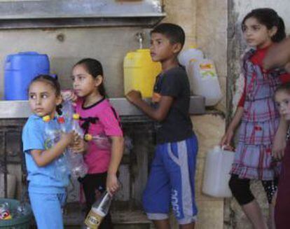 Crianças palestinas fazem fila para encher garrafas de água em Rafah.