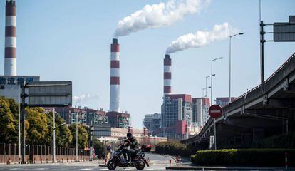 Um motociclista passa em frente a chaminés de uma central de geração elétrica em Xangai (China).
