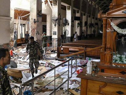 EDITORS NOTE: Graphic content / Sri Lankan security personnel walk past dead bodies covered with blankets amid blast debris at St. Anthony's Shrine following an explosion in the church in Kochchikade in Colombo on April 21, 2019. - A string of blasts ripped through high-end hotels and churches holding Easter services in Sri Lanka on April 21, killing at least 156 people, including 35 foreigners. (Photo by ISHARA Séc. KODIKARA / AFP)