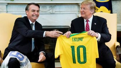 Bolsonaro entrega uma camisa da seleção brasileira a Trump na Casa Branca.