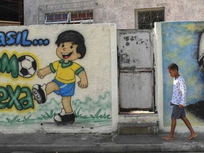 Menino caminha diante de grafites sobre a Copa no Rio.