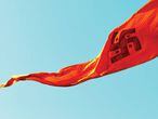 La bandera con la cruz gamada hindú ondea en el gran encuentro de peregrinaje (<em>kumbh mela</em>) Simhasth en la ciudad de Ujjain, en Madhya Pradesh (India). En el hinduísmo, la esvástica representa la idea de dios, Brahman. Si gira a la derecha (en sentido dextrógiro, como la nazi), simboliza la evolución del universo encarnada por el dios creador Brahmá. En cambio, en el sentido contrario a las agujas del reloj, representa la involución del universo, obra del dios destructor Shivá. Los círculos corresponden a los cuatro puntos cardinales, símbolo de estabildad. |