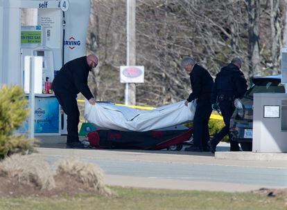 Pessoal sanitário remove um cadáver em um posto de gasolina de Enfield, na Nova Escócia, no domingo.