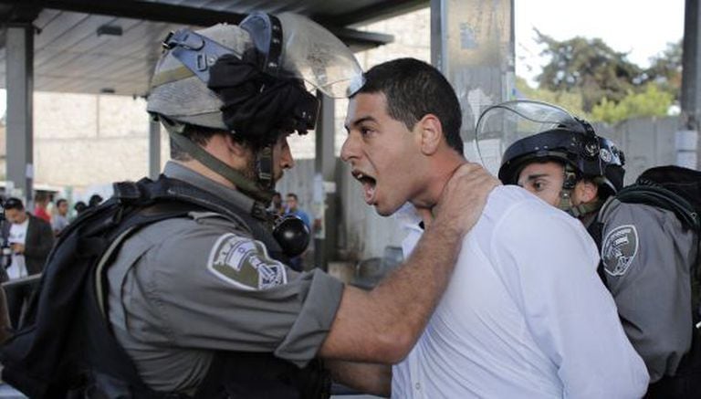 Um policial israelense prende um palestino em protesto em Jerusalém.