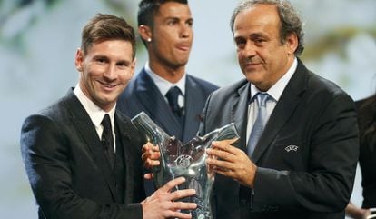 Messi recebe o prêmio de melhor jogador da última Liga dos Campeões das mãos do presidente da UEFA, Michel Platini. No fundo, Cristiano Ronaldo.