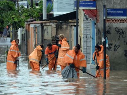 Garis tentam limpar bueiros de área inundada do Rio de Janeiro.
