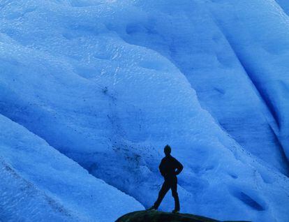 Um turista diante do gelo azul do glaciar Svartisen, ao norte de Noruega.