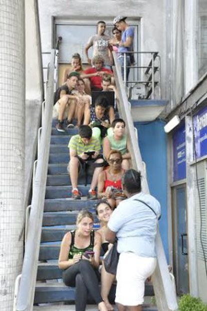 Usuários de WiFi público em uma escada do hotel Havana Livre.