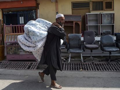 Um afegão vai ao mercado de segunda mão no bairro de Khari Khana, em Cabul, para vender um colchão e sua roupa de cama, no domingo.
