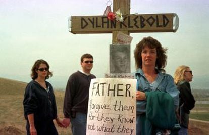Pessoas visitando o ponto no qual foi feita uma homenagem às vítimas do massacre de Columbine, em Littleton, Colorado. Na imagem, una cruz com a foto e o nome de Dylan Klebold e um cartaz no qual se lê: “Pai, perdoai-os porque eles não sabem o que fazem" (Jesus).