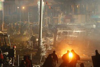 Manifestantes e policiais separados por um caminh&atilde;o queimado em Kiev. 