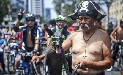 Um idoso posa com seu animal de estimação durante uma marcha de ciclistas nus.