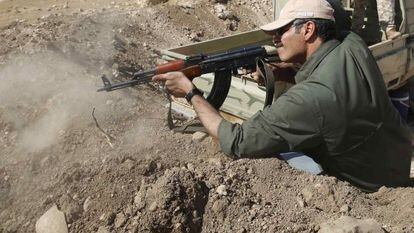 Um miliciano curdo dispara em direção a Baretle, cidade controlada pelo EI.