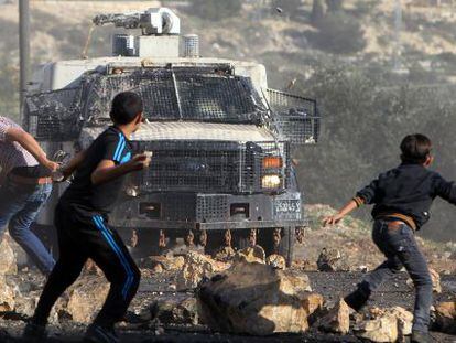 Palestinos lançam pedras em veículo militar israelense.