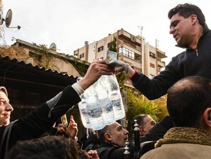 Um homem vende garrafas de água mineral num bairro de Damasco.