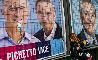 Mulher passa diante de cartazes de propaganda de Mauricio Macri e Alberto Fernández em uma rua de Buenos Aires.