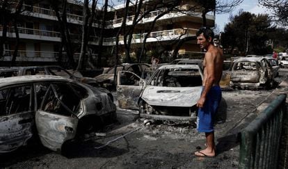Um homem observa o estado em que ficaram vários carros calcinados em Mati (Grécia), nesta segunda-feira.