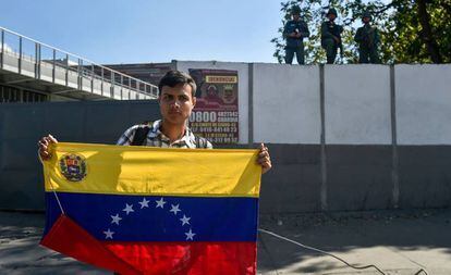 Venezuelano com a bandeira do país em frente a um quartel