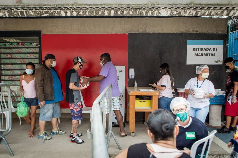 Participantes do projeto Mãos de Maria distribuem pratos de comida.