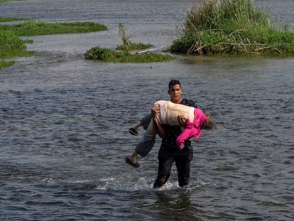 Um migrante venezuelano cruza o rio Grande, na fronteira entre os EUA e o México, carregando uma idosa, na quarta-feira.