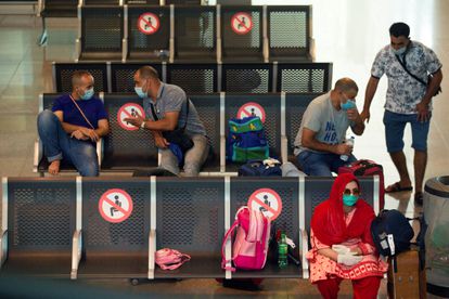 Viajantes com máscaras protetoras aguardam seu voo no aeroporto de Barcelona.