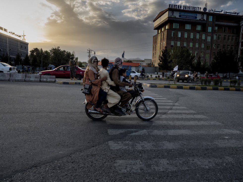 Uma família afegã passa de moto por uma rua de Cabul perto de um posto de controle dos fundamentalistas.