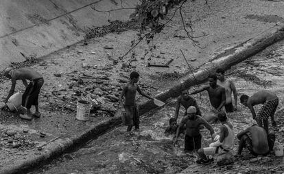 Jovens procuram objetos de valor nas águas do rio Guaire.